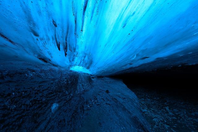 Blue light shining through the ice roof of a large ice cave chamber in Iceland
